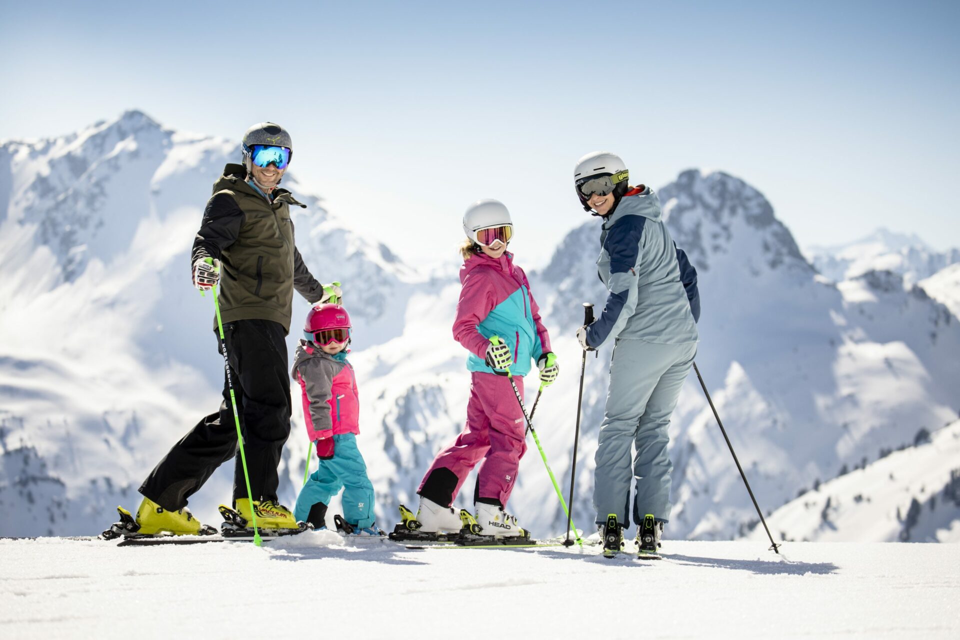 A family on skis standing on top of a mountain.