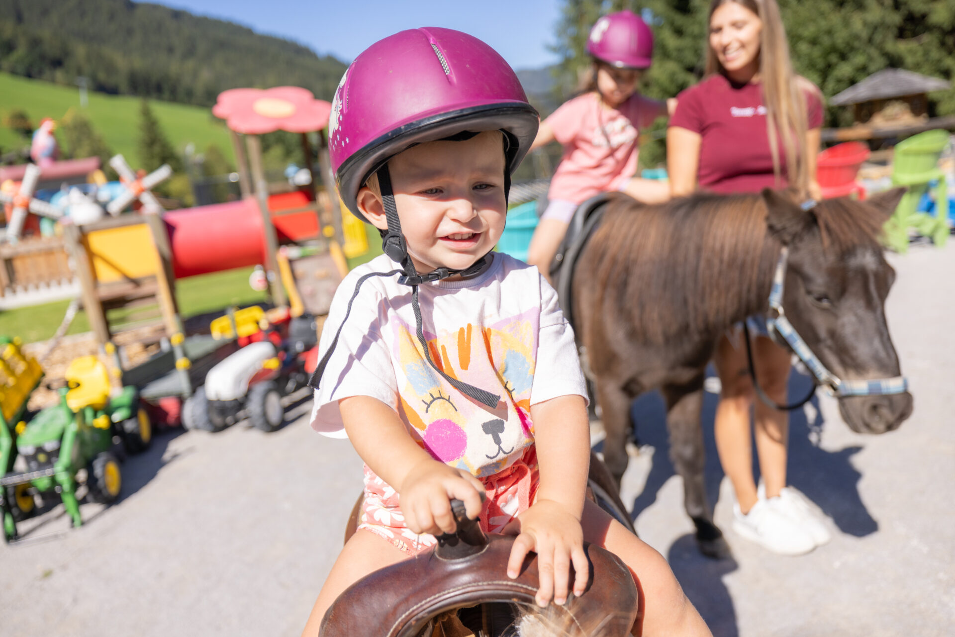 Eindrücke eines Kindes, das auf einem Pferd auf einem Spielplatz reitet.