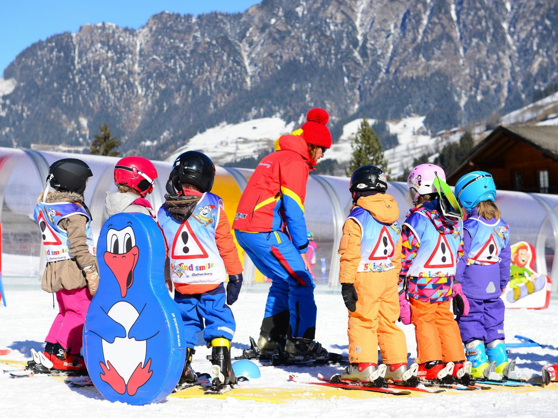 Skilehrerin bringt Kindern richtige Technik beim Skifahren bei.