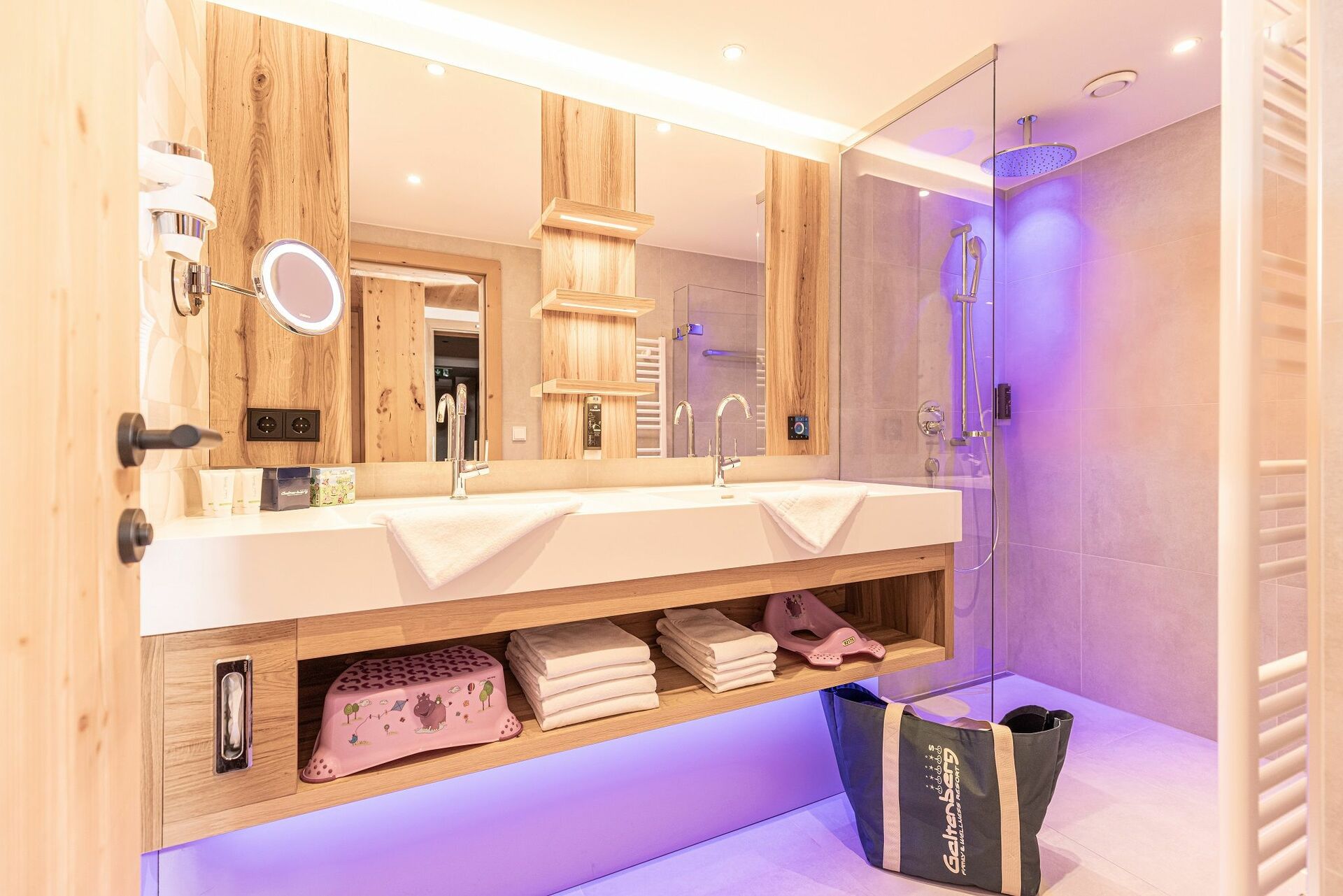 Ein Badezimmer mit Holzwaschbecken und lila Beleuchtung.