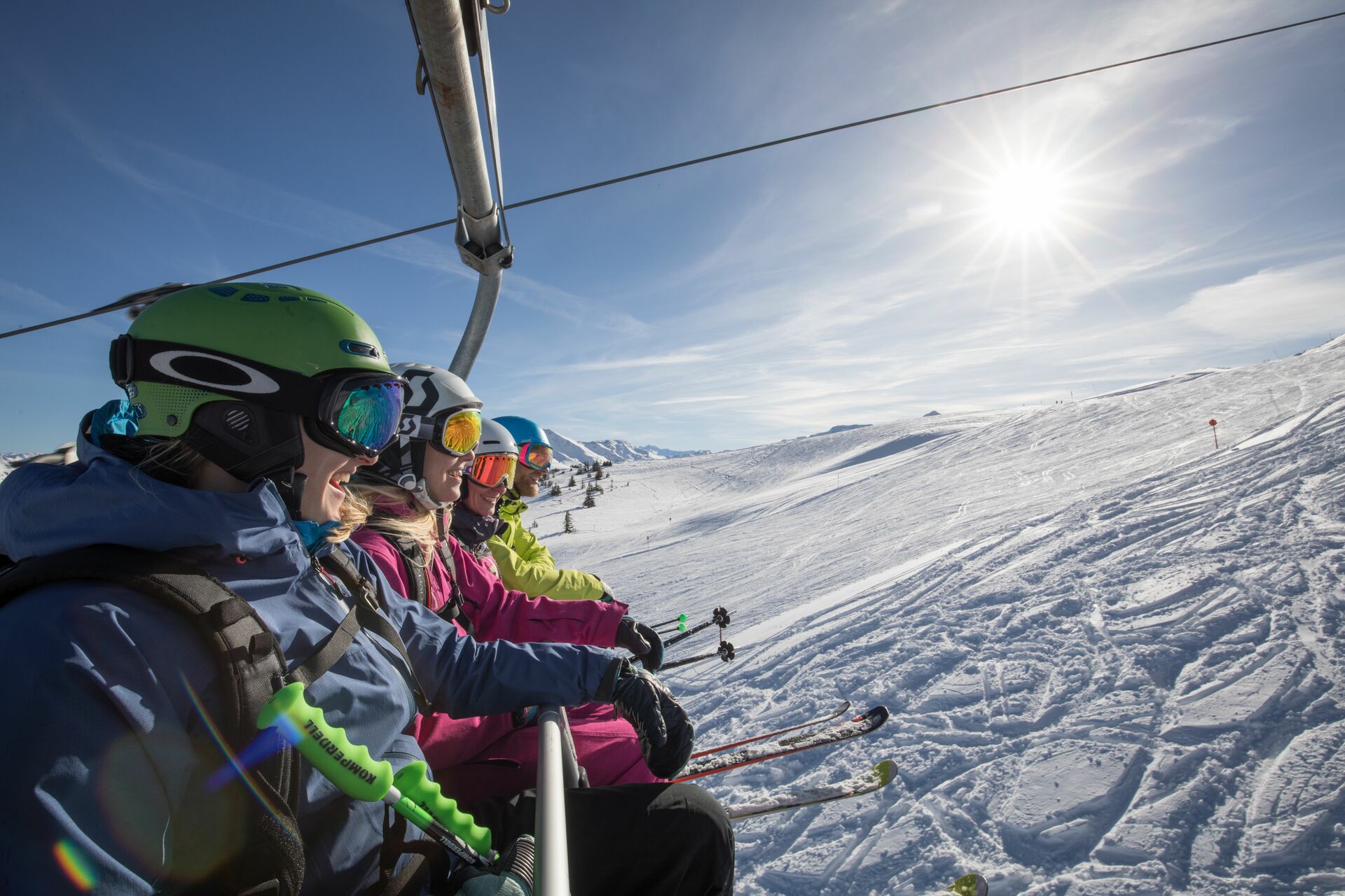 Skifahrer sitzen im Sessellift und schauen auf verschneite Berge.