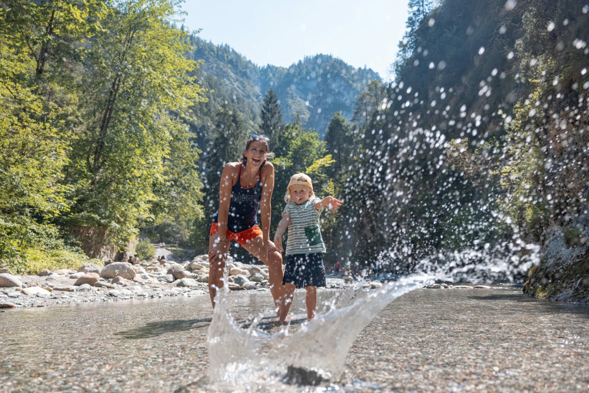 Eine Frau und ein Kind genießen das Wasserspiel in einem Fluss.