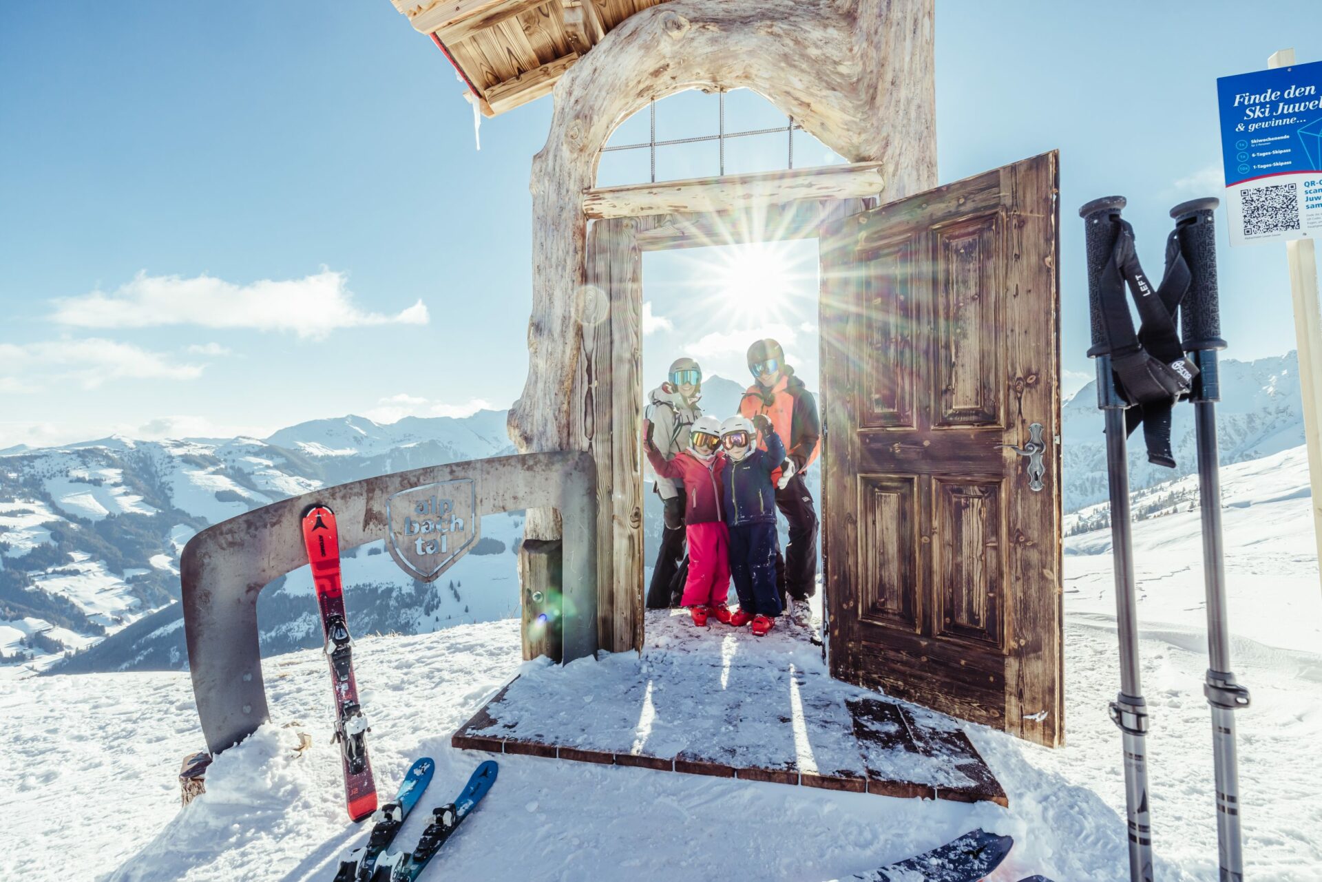 Familie steht auf Skiern auf einem Berg in einer Holztür.
