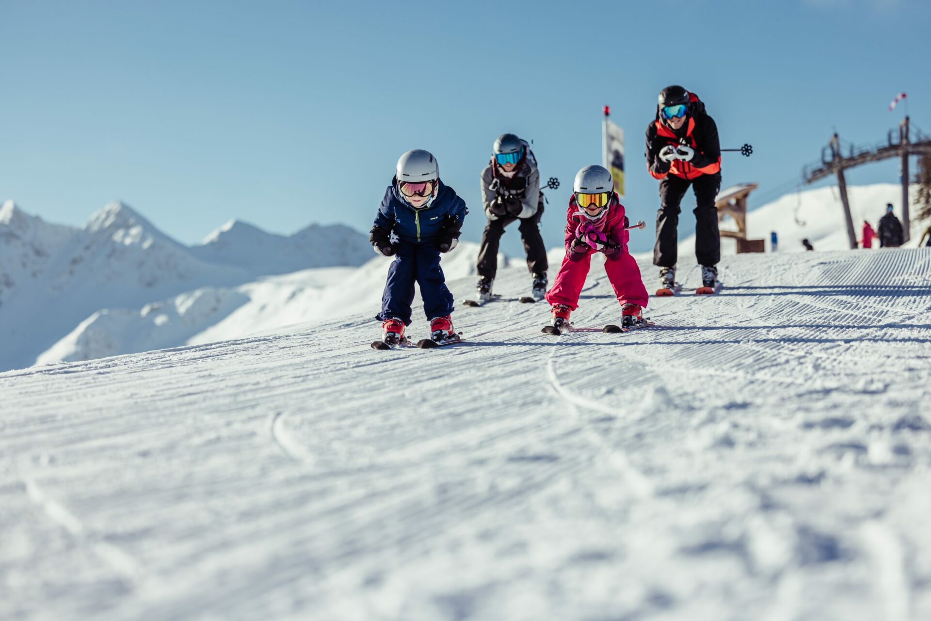 Familie fährt mit Skiern einen Berg hinab.
