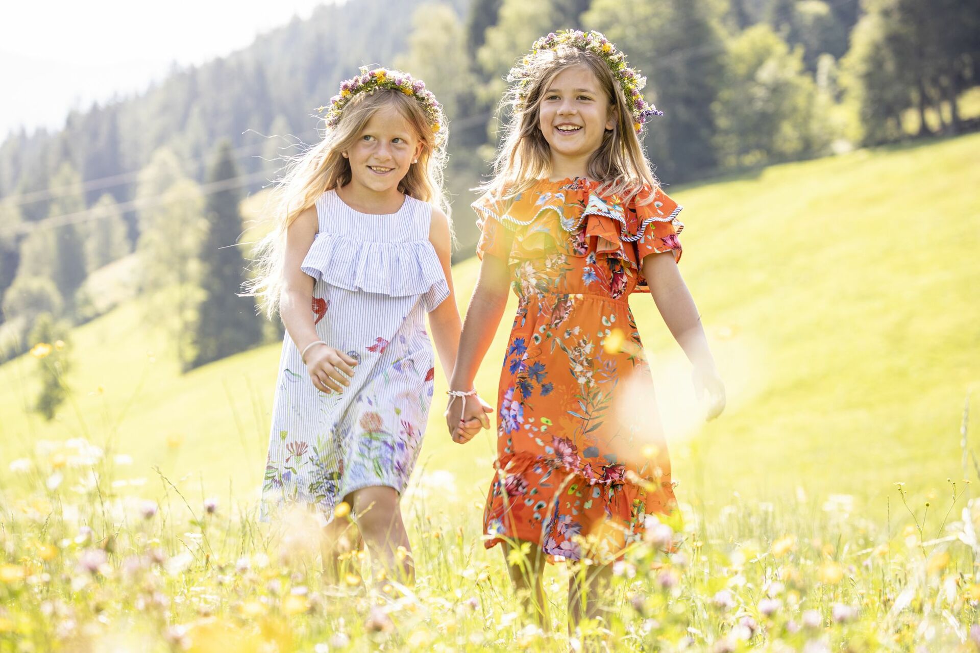 Zwei kleine Mädchen erkunden ein Blumenfeld im Kinderhotel Österreich.
