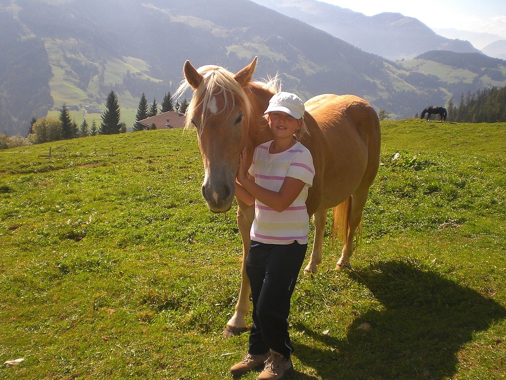 Ein Mädchen genießt einen aktiven Sommertag, indem es neben einem Pferd auf einem Feld steht.
