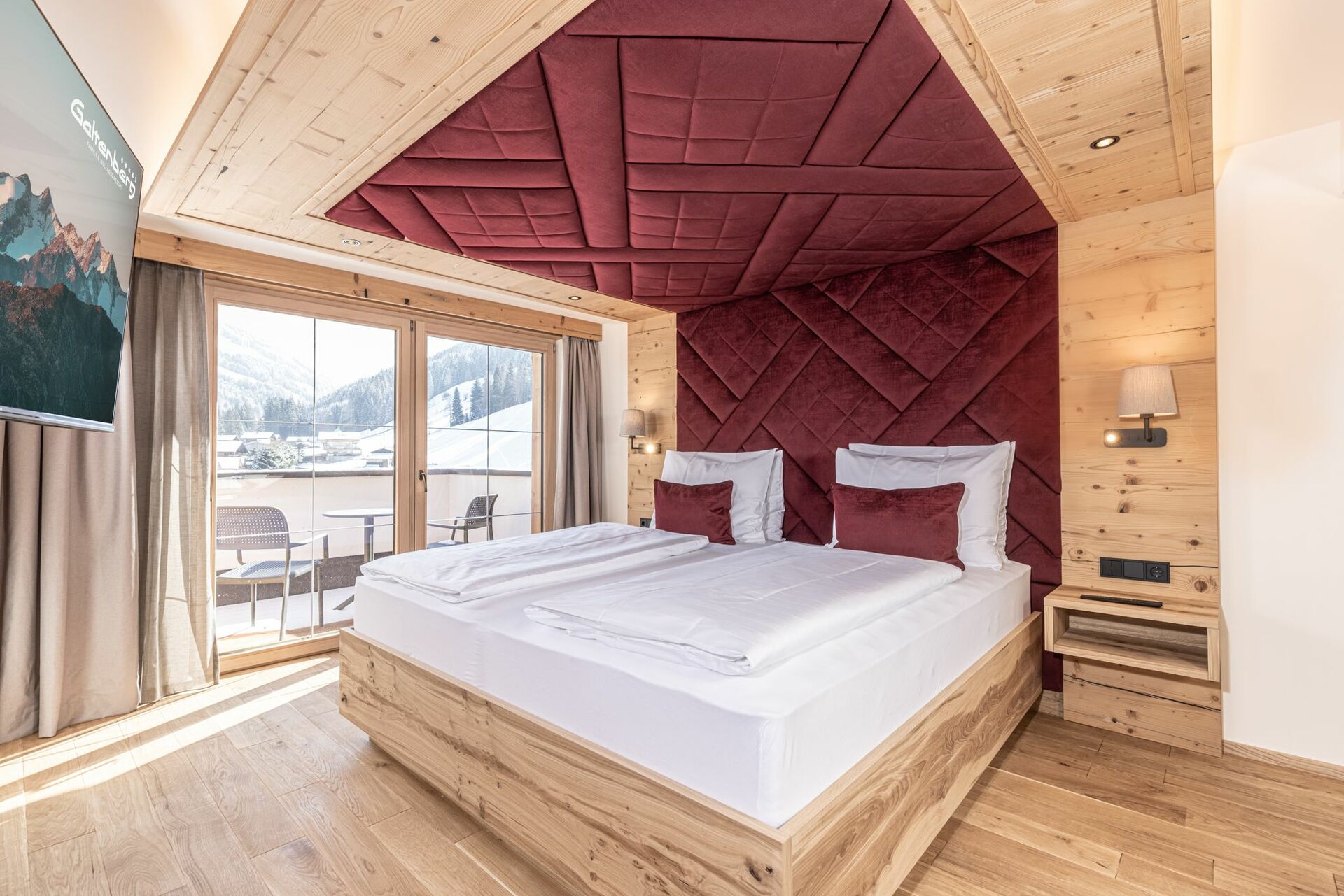 A romantic bed in a wooden room with a view of the mountains.