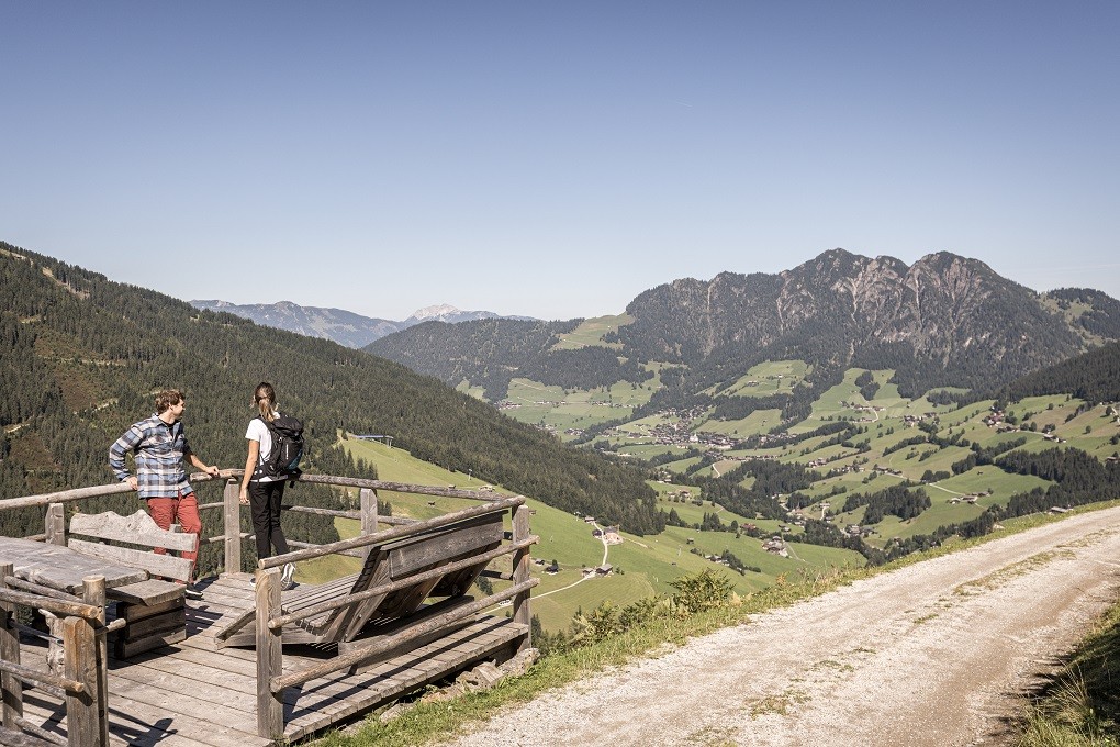 Zwei Personen im Galtenberg Resort stehen auf einer Holzplattform mit Blick auf ein Tal.